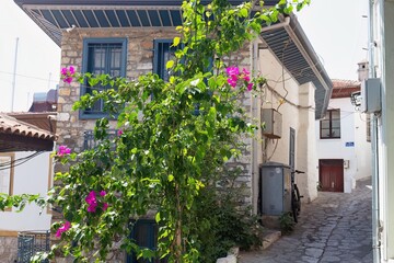Obraz premium A quaint street scene with bougainvillea in the foreground features stone buildings and cobblestone roads in old Marmaris - Mugla - Turkey