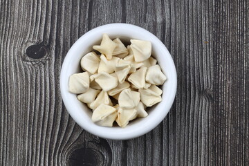 handmade manti (turkish ravioli type dumplings) on wooden   bowl, before cooking