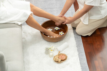 Woman indulges in blissful foot massage at luxurious spa salon while masseur give reflexology therapy in gentle day light ambiance resort or hotel foot spa. Quiescent