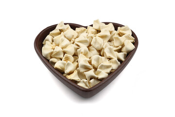 handmade manti (turkish ravioli type dumplings) on wooden heart shape bowl, before cooking. isolated on white background.