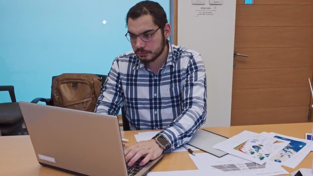Young Man Typing a Report on His Laptop for a Green Project