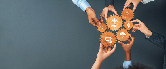 Diverse hands work together to hold gears symbolizing ethics, innovation, and justice against a neutral gray backdrop, illustrating collaboration and teamwork in action. Amity