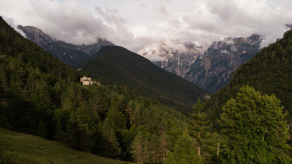 Obraz premium Majestic Mountain Valley with Lush Forests and Rugged Peaks Under a Cloudy Sky