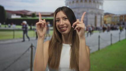 Young hispanic woman puckers lips gesture at tower in building near historic pisa site; playful flirtation.