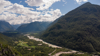 Naklejka premium Majestic Mountain Valley with Lush Forests and Rugged Peaks Under a Cloudy Sky