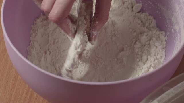 Close-up of woman coating raw hake fish pieces in flour before cooking, recorded with ambient sound.