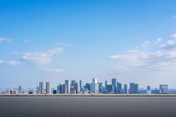 Modern city skyline under a bright blue sky with light clouds and a flat paved foreground