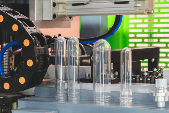 PETG plastic preforms for bottle making on the conveyor belt before the hot blow molding machine