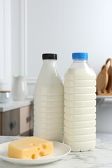 Milk and cheese on white marble table indoors. Dairy products