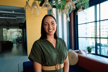 Portrait of smiling young businesswoman in smart casual looking at camera in office during daytime