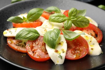 Tasty salad Caprese with mozzarella, tomatoes, basil and spices on table, closeup