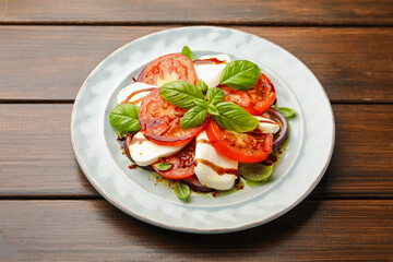 Tasty salad Caprese with mozzarella, tomatoes, basil and spices on wooden table, closeup