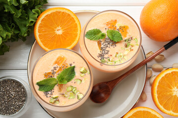Superfood. Tasty smoothie with chia seeds, mint, pistachio and oranges on white wooden table, flat lay