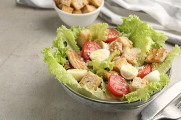 Delicious salad with croutons, chicken, quail eggs, tomato and cheese on grey table, closeup