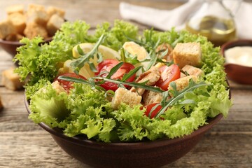 Delicious salad with croutons served on wooden table, closeup