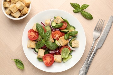 Delicious salad with croutons, vegetables and basil on wooden table, flat lay