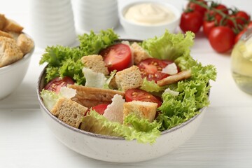 Delicious salad with croutons and ingredients on white wooden table, closeup