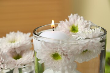 Burning candle and flowers in glass of water on blurred background, closeup
