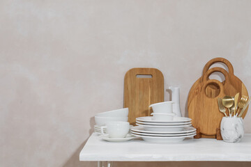 Clean dishware and cutting boards on table near light wall. Space for text