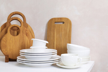 Different clean white dishware and wooden cutting boards on counter in kitchen