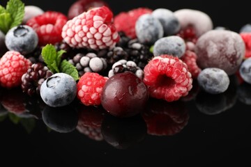 Many different frozen berries and mint on black table, closeup
