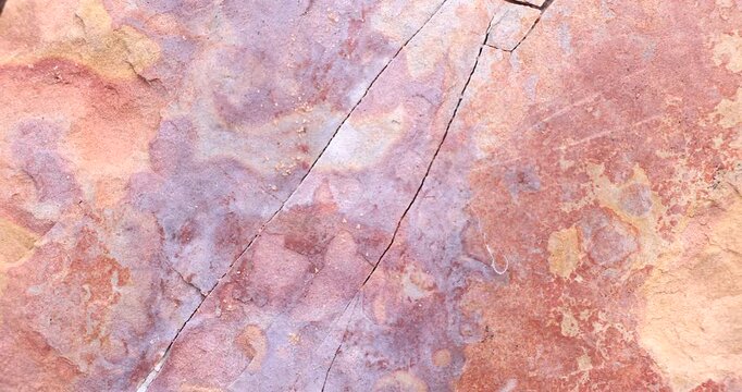 Closeup of smooth abstract sunset color rock with cracks and surface weathered pattern