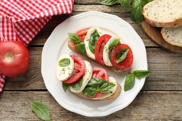 Delicious sandwiches with mozzarella cheese, tomatoes and basil on wooden table, flat lay