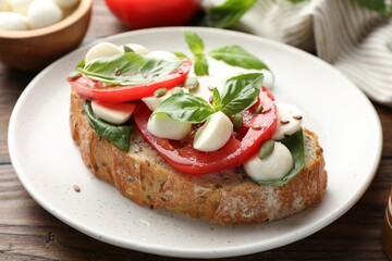 Delicious sandwich with mozzarella cheese, tomatoes and basil on wooden table, closeup
