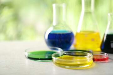 Laboratory glassware with different samples on light grey table outdoors, closeup. Solution chemistry