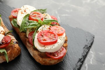 Delicious sandwiches with mozzarella cheese, tomatoes and basil on black marble table, closeup. Space for text