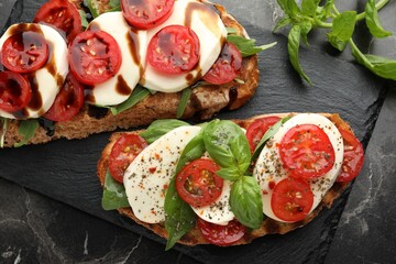 Delicious sandwiches with mozzarella cheese and tomatoes on black marble table, flat lay