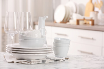 Different clean white dishware and glasses on marble table indoors, space for text