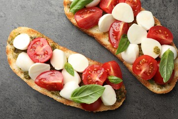 Delicious sandwiches with mozzarella cheese, tomatoes and basil on grey textured table, flat lay