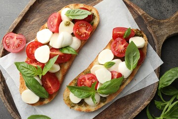 Delicious sandwiches with mozzarella cheese, tomatoes and basil on grey textured table, flat lay