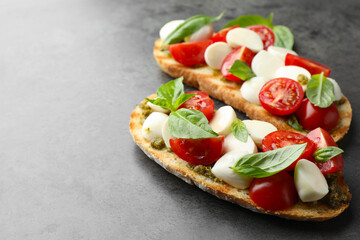 Delicious sandwiches with mozzarella cheese, tomatoes and basil on grey textured table, closeup. Space for text
