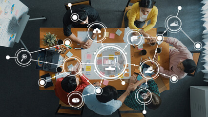 An overhead view of a business meeting showcasing a diverse team collaborating on analytics and data-driven strategies for project improvements and future success. Amity