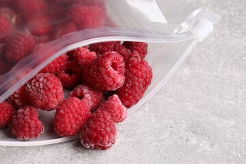 Ripe frozen raspberries in open zipper bag on grey textured table, closeup © New Africa