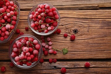 Ripe frozen red currants on wooden table, flat lay. Space for text