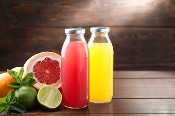 Tasty juices in glass bottles, fresh fruits and mint on wooden table