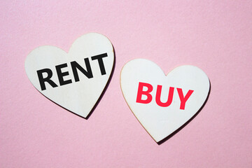 Rent or Buy symbol. Concept word Rent or Buy on wooden hearts. Beautiful pink background. Business and Rent or Buy concept. Copy space