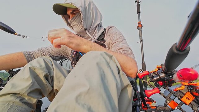 Kayaking and fishing pov footage. Angler in kayak hooking nightcrawler or worm earthworm to fish. Floating by in the middle of lake during morning. Active powersport fish game.