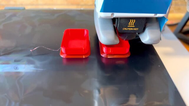 3d printer creating two red plastic objects