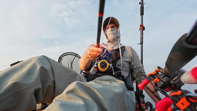 Kayaking at lake, POV of fisherman trolling casting and reeling during summer morning sunrise. Aquatic powersport and water sports. Kayaker fishing at lake. Kayak sailing view on person in watercraft.