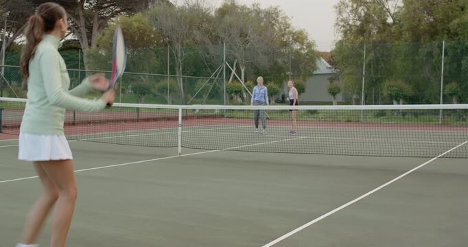 Female friends rallying tennis ball serving volleying lobbing tapping rackets at net, copy space