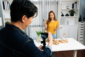 Asian beautiful woman food specialist blogger teaching how to mixed salad easy cooking in glass blow on live channel recorded by smart cameraman streaming lifestyle on social media concept. Infobahn.