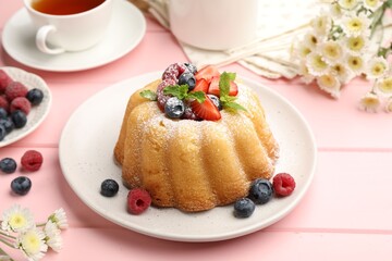 Delicious bundt cake with powdered sugar, berries and mint on pink wooden table, closeup