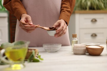 Making natural scrub. Woman adding coffee into bowl at white wooden table, closeup