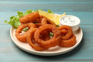 Fried squid rings served with sauce on light blue wooden table, closeup