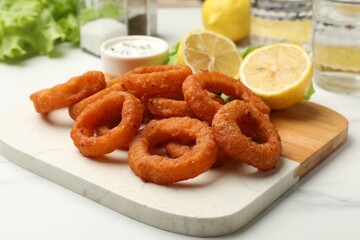 Fried squid rings served with sauce on white marble table, closeup