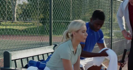 Post-rally, diverse coach and players grabbing water and towel while talking tactics at benchside - Powered by Adobe